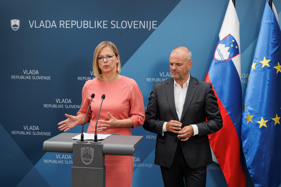Ministra Sanja Ajanović Hovnik in Uroš Brežan v malem novinarskem središču podajata izjavo po seji vlade.