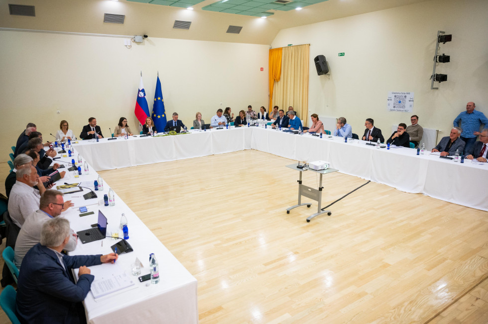 Predsednik vlade in ministri sedijo za omizjem na seji vlade.