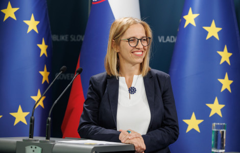 20250619 01451859 (A smiling woman standing at a podium with microphones, in front of EU and Slovenian flags.)