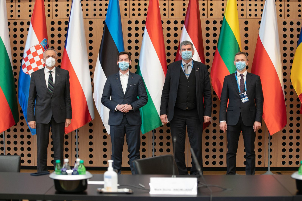Skupinska fotografija, osebe nosijo maske, v ozadju zastave.