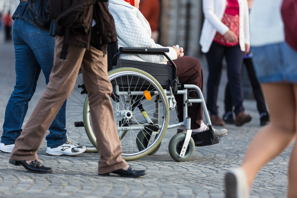 Gospa na invalidskem vozičku med množico ljudi