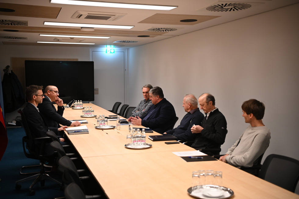 Moški sedijo za dolgo mizo.