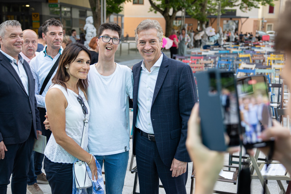 Predsednik vlade na sliki stoji pred kamero z dvema osebama