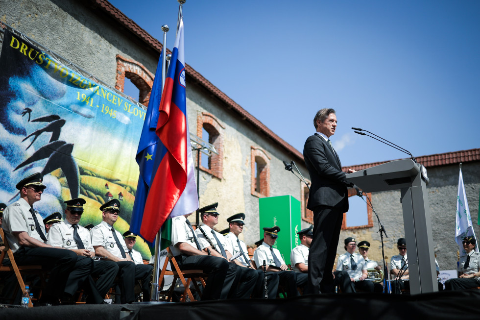 Predsednik vlade stoji za govorniškim pultom na prireditvi