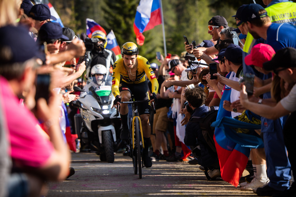 a road cyclist in a yellow jersey surrounded on both sides by fans