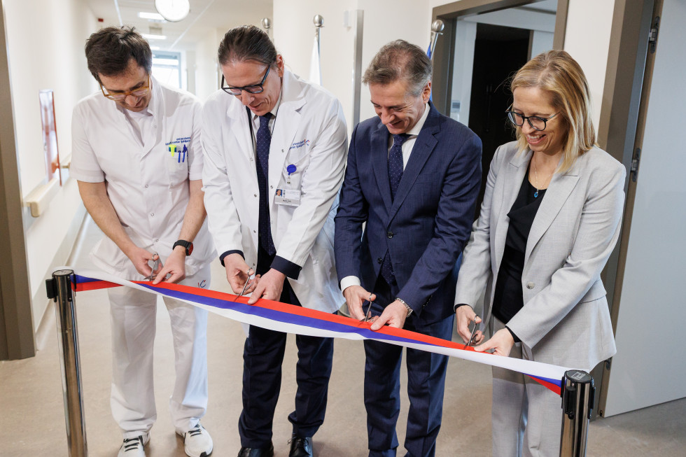 Predsednik vlade stoji in reže slavnostni trak