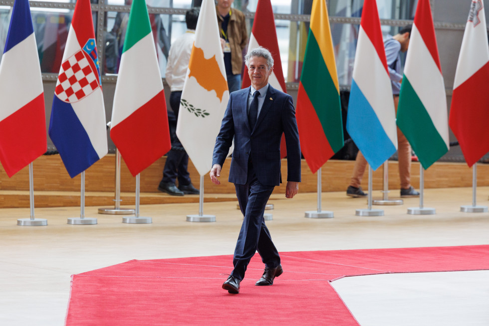 Predsednik vlade dr. Robert Golob hodi po rdeči preprogi, v ozadju so zastave držav članic EU