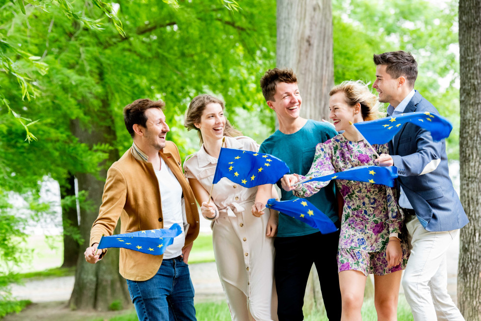 A group of young boys and girls hold European flags in front of them.