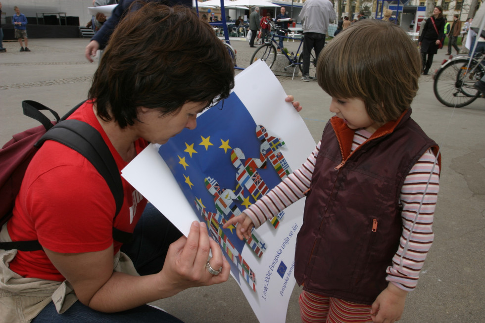 Deklica si ogleduje plakat z evropsko zastavo in zastavami držav članic.