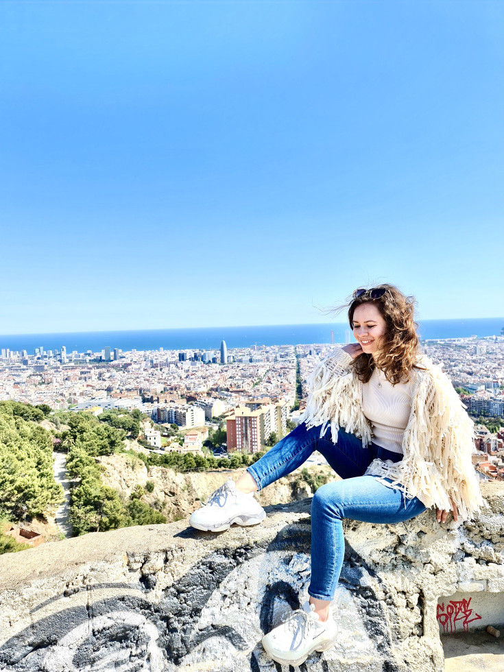 Ženska sedi na obzidju, v ozadju pogled na Barcelono.