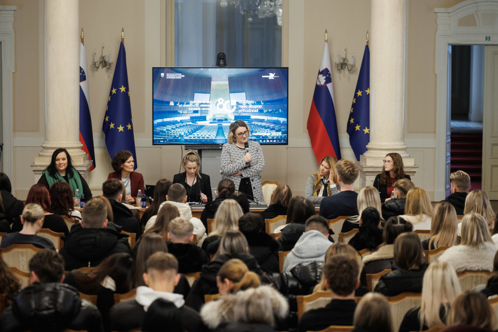 Skupina treh mladih žensk in ena starejša ženska stoji pred občinstvom v okrašeni sobi ter drži nagrade.