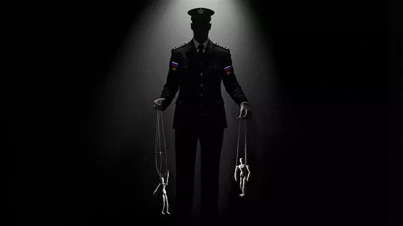 Moški v uniformi, ki ga osvetljuje snopu svetlobe, v rokah drži vrvice, na katerih visijo majhne lutke.