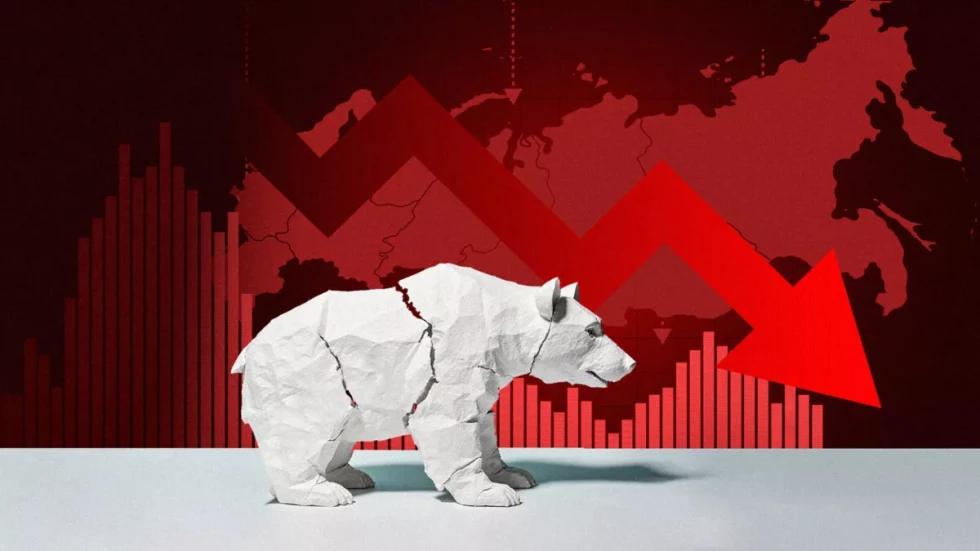 Bel medved iz papirja, v ozadju je zemljevid Rusije in velik rdeč puščast graf, obrnjen navzdol.