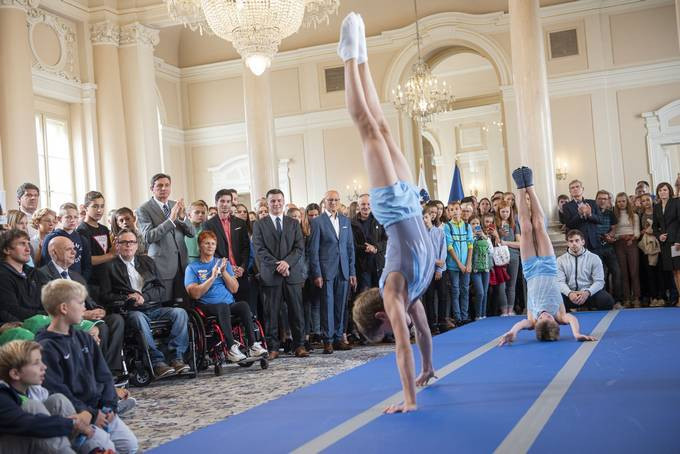 otroka ob izvajanju gimnastičnih prvin, med gledalci predsednik republike in ostali gostje v veliki dvorani predsedniške palače