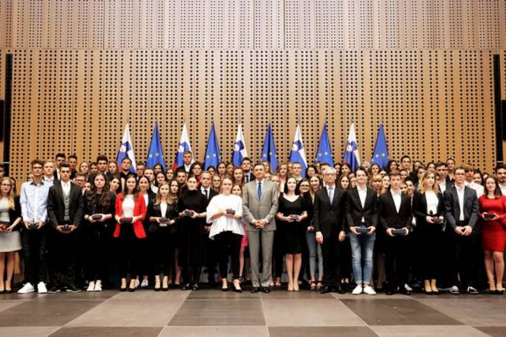 skupinska fotografija predsednika z maturanti pred zastavami v dvorani Grandis Kongresnega centra Brdo