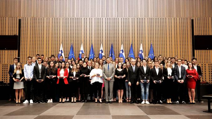 skupinska fotografija predsednika z maturanti pred zastavami v dvorani Grandis Kongresnega centra Brdo