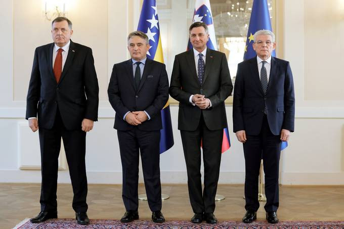 slovenski predsednik in gostje pred zastavami v veliki dvorani predsedniške palače
