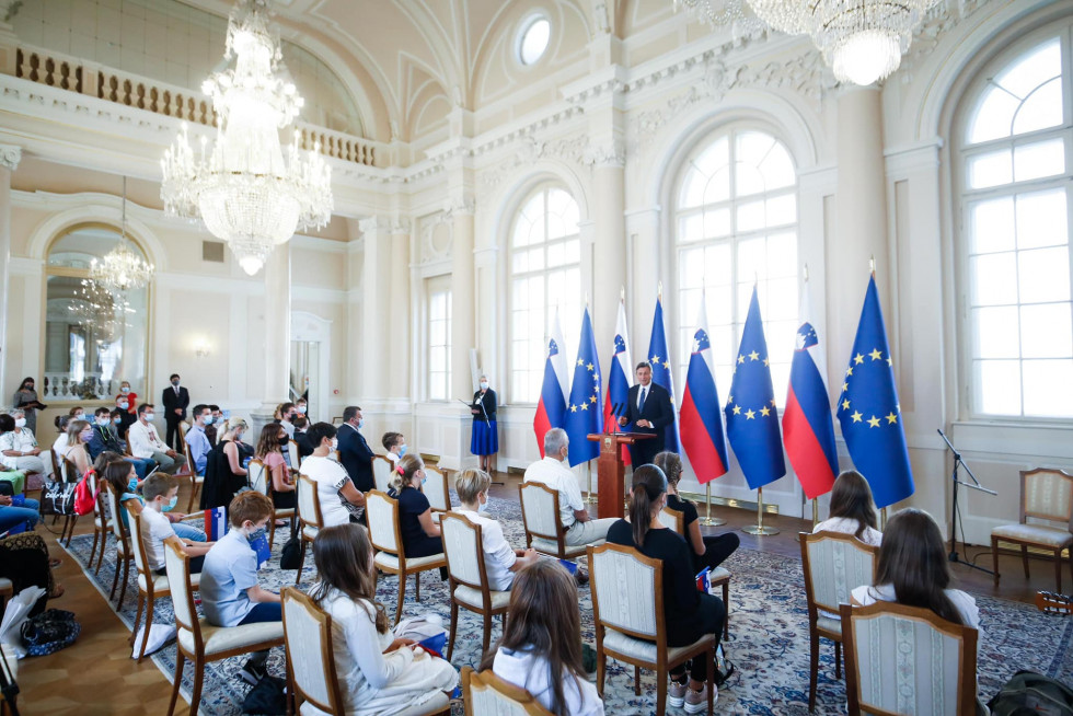 predsednik republike ob govoru pod zastavami in sedeči gostje dogodka v veliki dvorani Predsedniške palače 