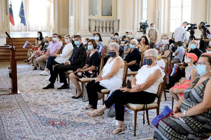 sedeči udeleženci dogodka v veliki dvorani Predsedniške palače (vsi v maskah)
