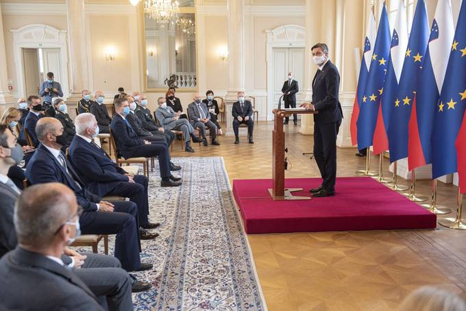 predsednik ob govorniškem pultu pred zastavami in sedeči gostje v veliki dvorani predsedniške palače