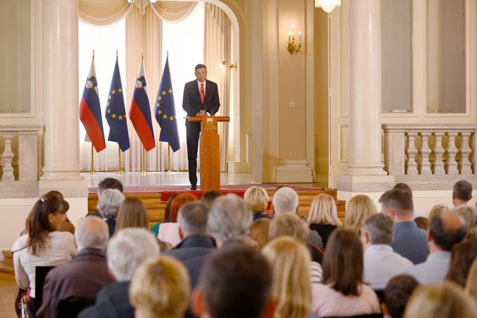 predsednik ob govorniiškem pultu pred gosti v veliki dvorani predsedniške palače 