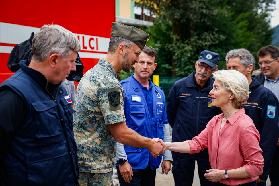Predsednica Evropske komisije Ursula von der Leyen se v Črni na Koroškem rokuje s pripadnikom tujih sil, ki so pomagali pri odstranjevanju posledic poplav.