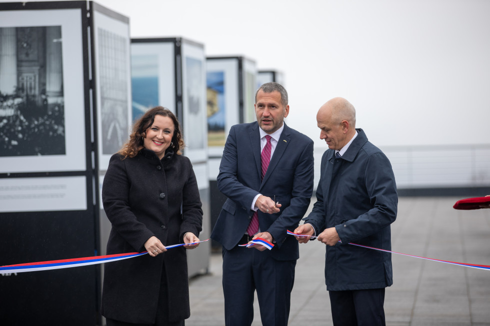 Petra Bezjak Cirman, Damir Črnčec in Janko Boštjančič so prerezali trak, v ozadju panoji s fotografijami