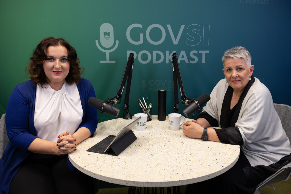 Dve ženski sedita za okroglo mizo z mikrofonoma, za njima napis GOVSI podkast