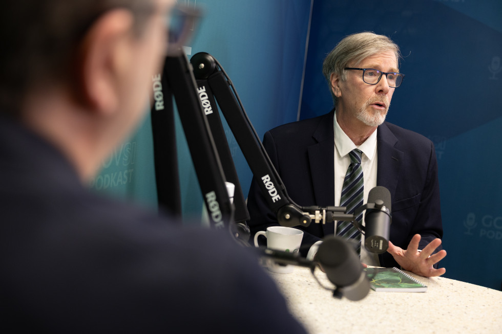 A man is sitting at a table with a microphone.