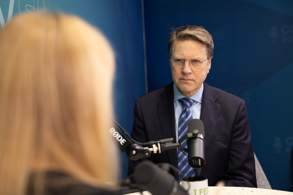 A man sitting, in front of him is a microphone