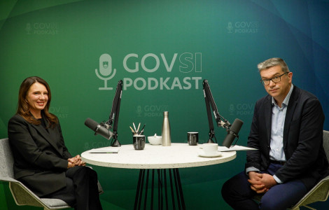 324 0253.00 02 37 18.Still001 2 (Nina Gregori and Zoran Potič sitting at a table with microphones at the podcast studio.)