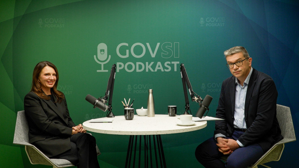 Nina Gregori and Zoran Potič sitting at a table with microphones at the podcast studio.