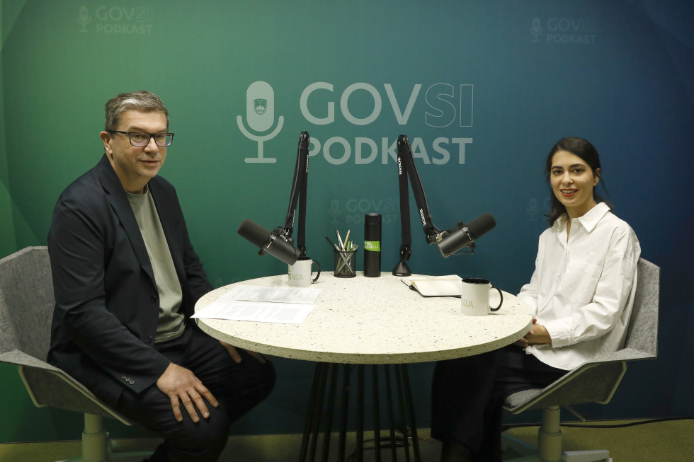 A man and a woman sitting at a round table with microphones.