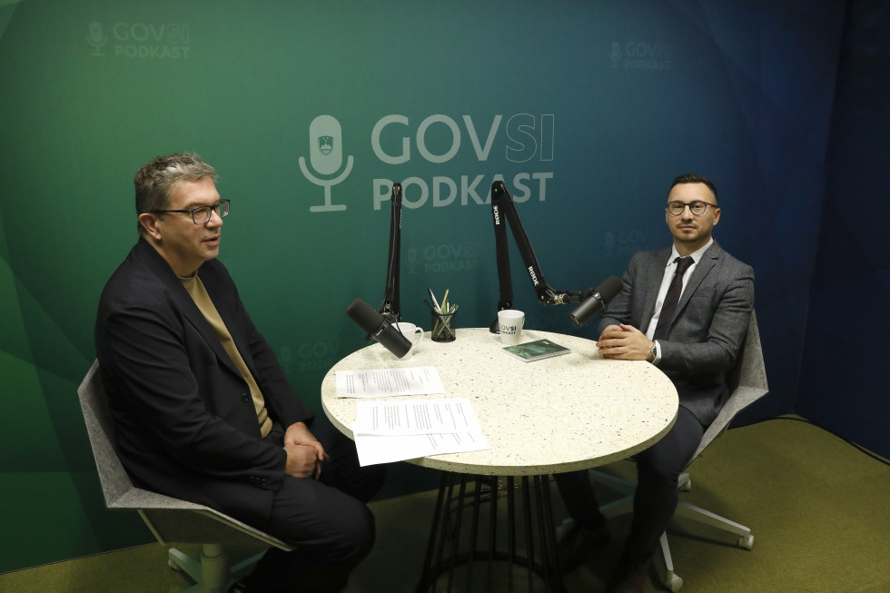 Two men sitting at a round table with microphones.