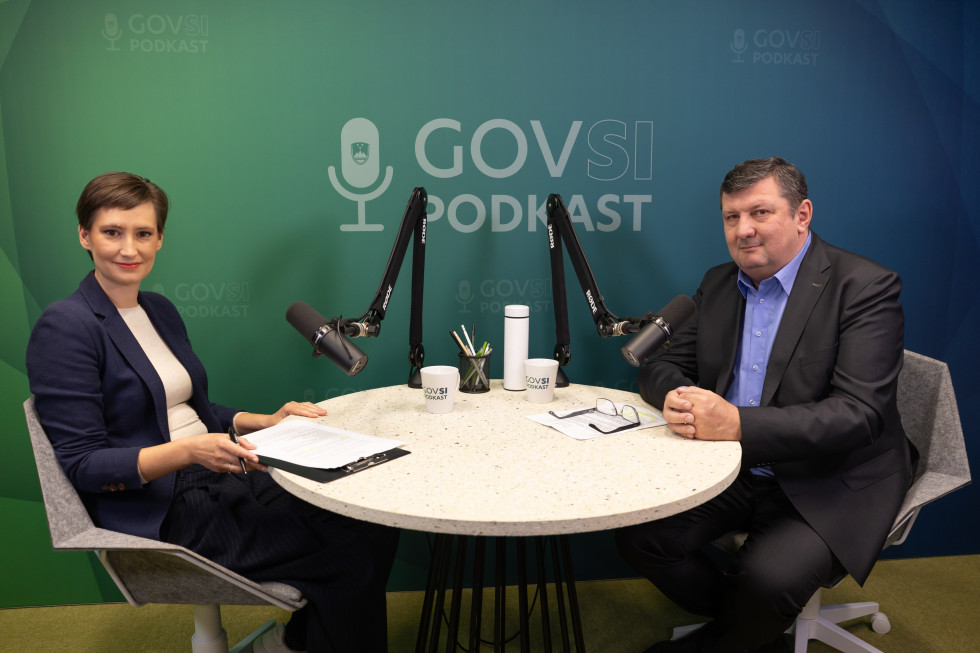 A woman and a man sitting at a round table with microphones.