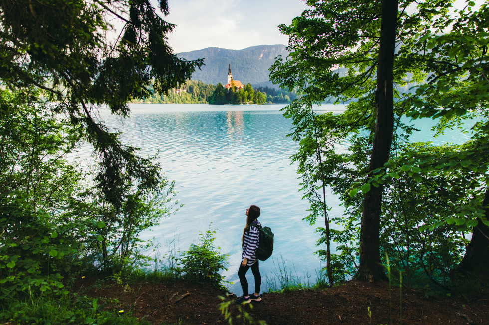 Woman traveler exploring the scenic mountain lake Bled in Julian Alps.