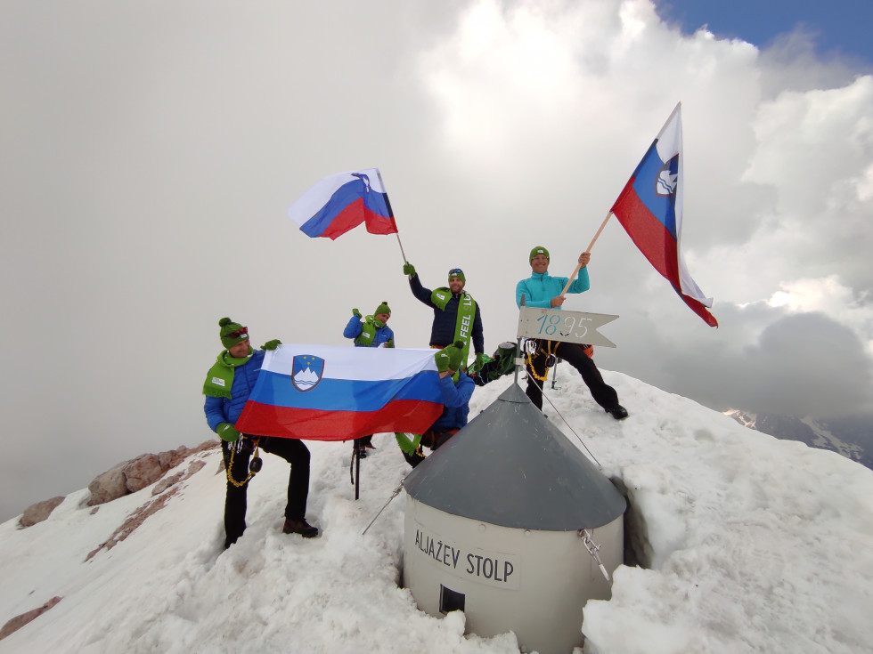 Fantje ob Aljaževe stolpu mahajo s slovenskimi zastavami.
