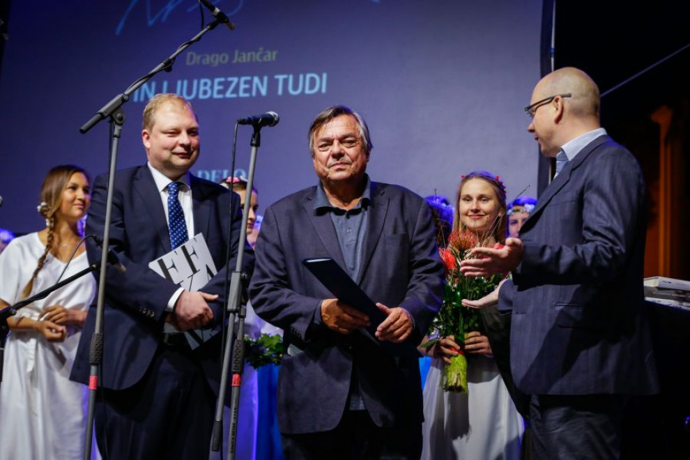 Drago Jančar with the prize in his hands stands on stage. 