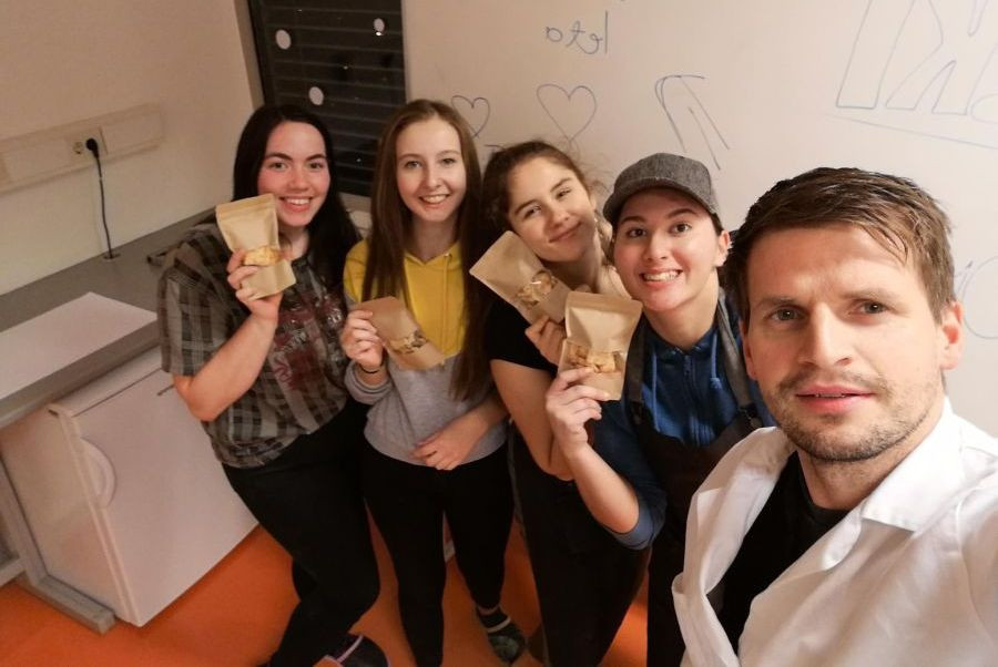 Schoolgirls with a teacher. They've got a homemade product in their hands.