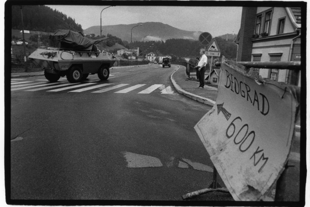 Tank na cesti, narisana tabla z napisom Beograd 600 km in s puščico.
