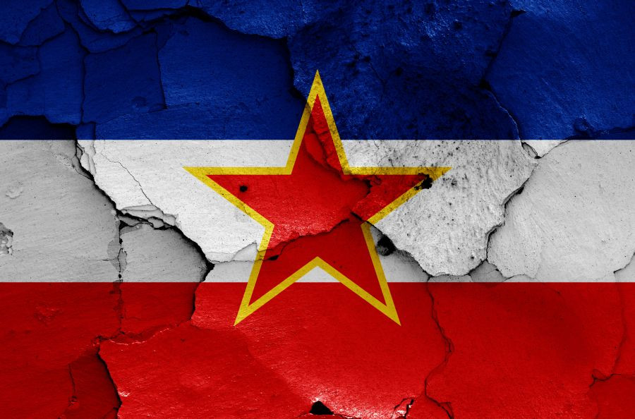Narisana jugoslovanska zastava na razpadajočem in razpokanem zidu.