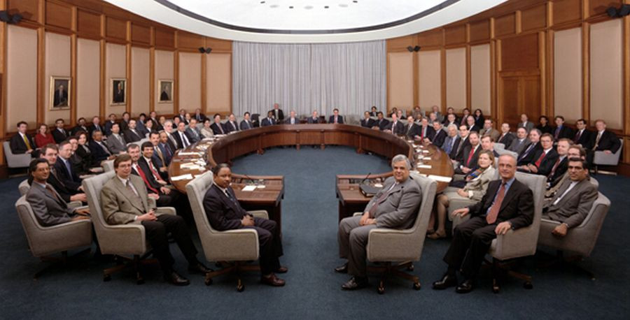 Guvernerji sedijo v polkrogu v dvorani.