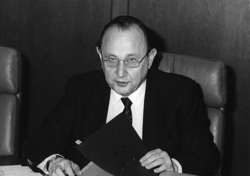 Hans Dietrich Genscher sedi za mizo in odpira mapo.