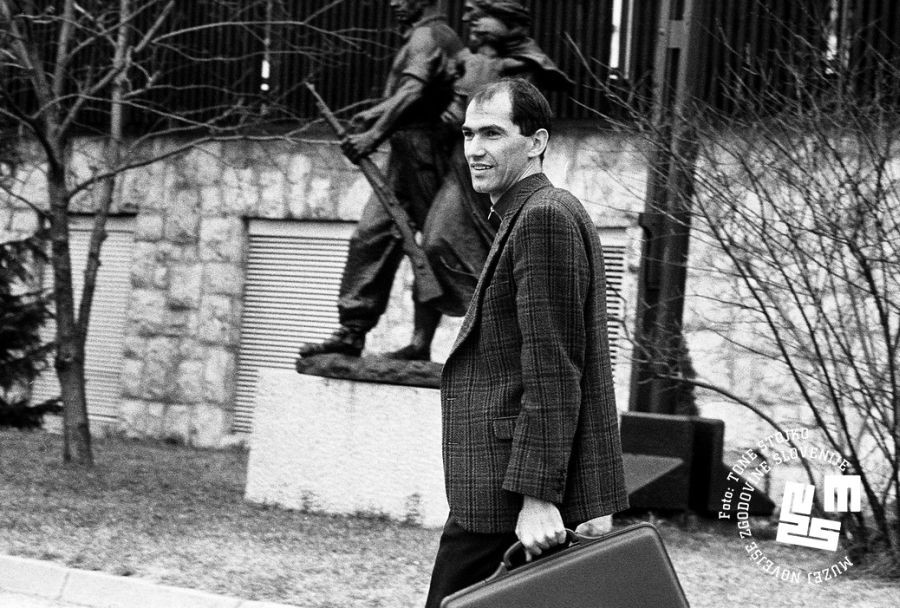 Janez Janša s kovčkom v roki hodi po cesti.