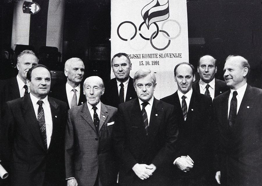Športniki in predstavniki OKS ter Republike Slovenije. V ospredju Leon Štukelj, Milan Kučan, in Janez Kocijančič. V ozadju pano z znakom OKS.