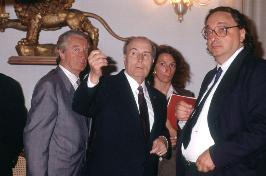 Roland Dumas stoji poleg Francoisa Mitterranda, ki z dvignjeno roko nekaj kaže, poleg njega je Gianni de Michelis. Zadaj stoji prevajalka.