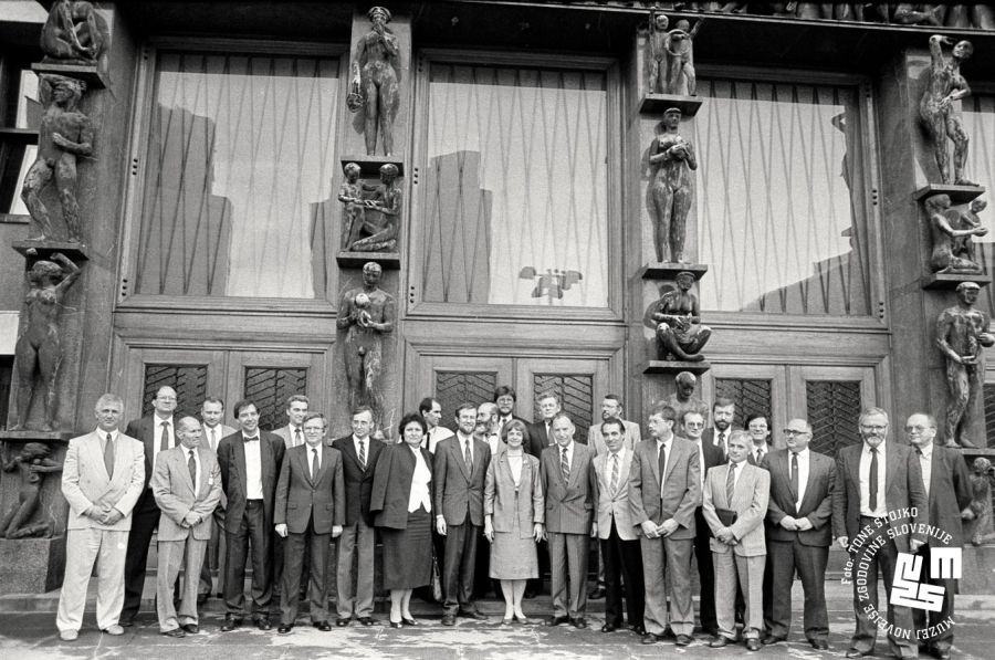 Predstavniki vlade stojijo pred stavbo Državnega zbora RS.