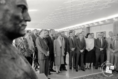 Members of the government stand in a semicircle in the chamber.