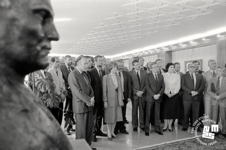 Člani slovenske vlade stojijo v dvorani.