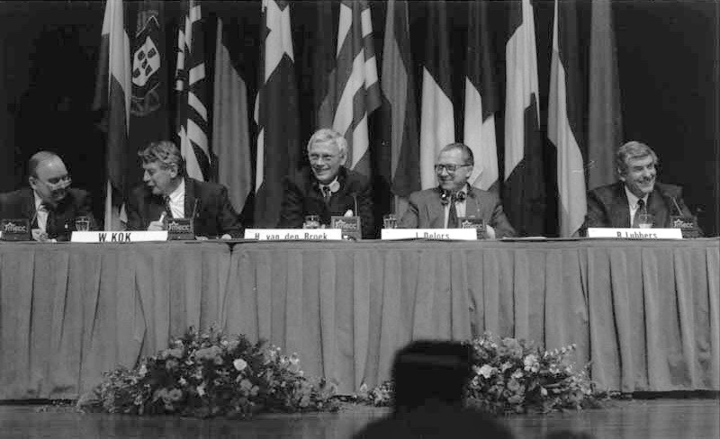 Pet voditeljev držav ES sedijo za mizo na govorniškem odru.